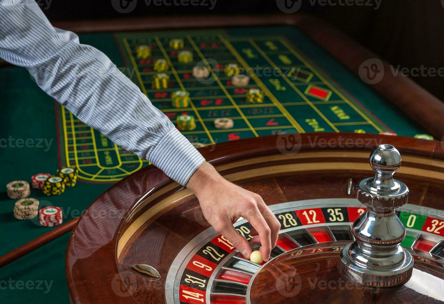 Roulette wheel and croupier hand with white ball in casino photo