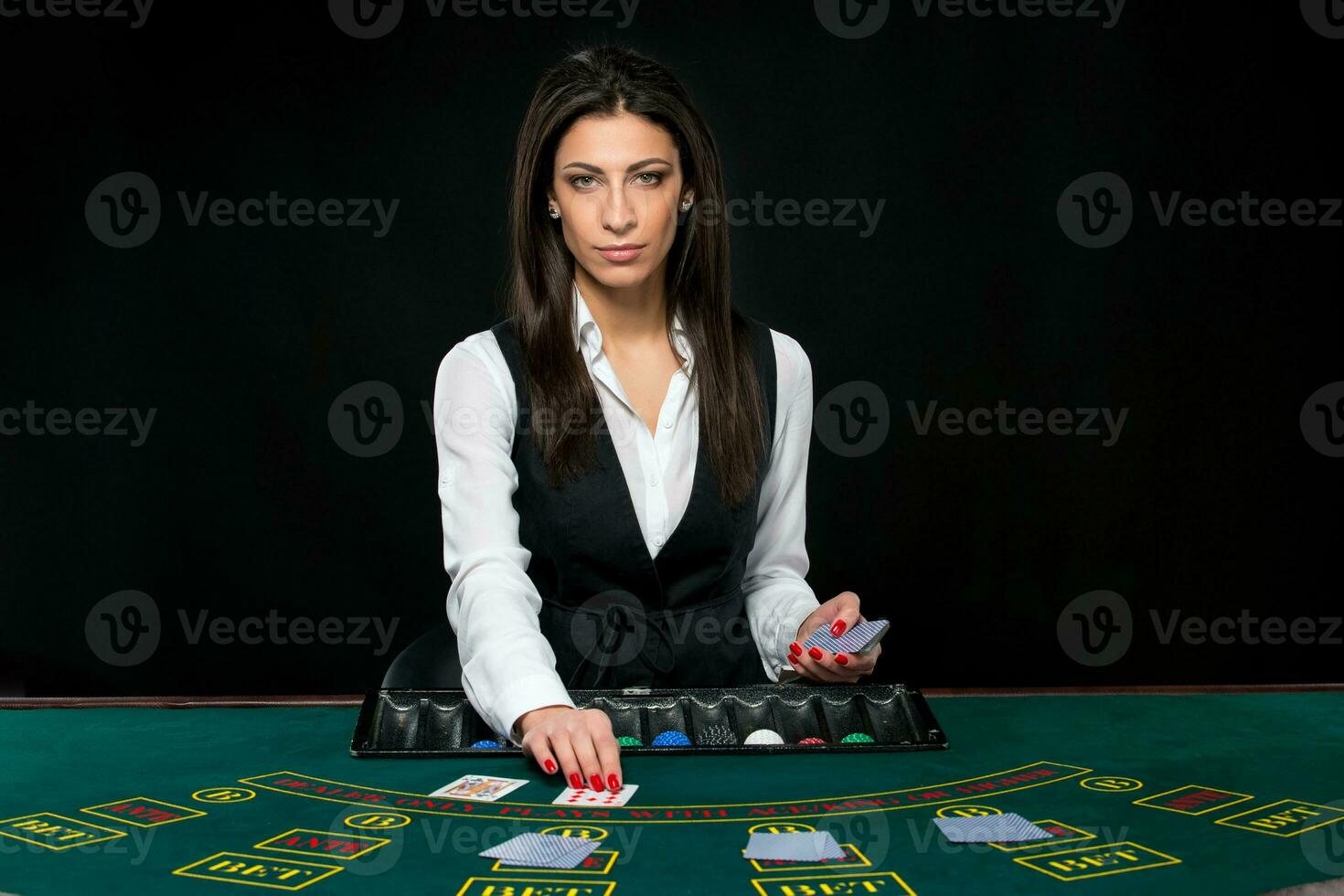 The beautiful girl, dealer, behind a table for poker photo