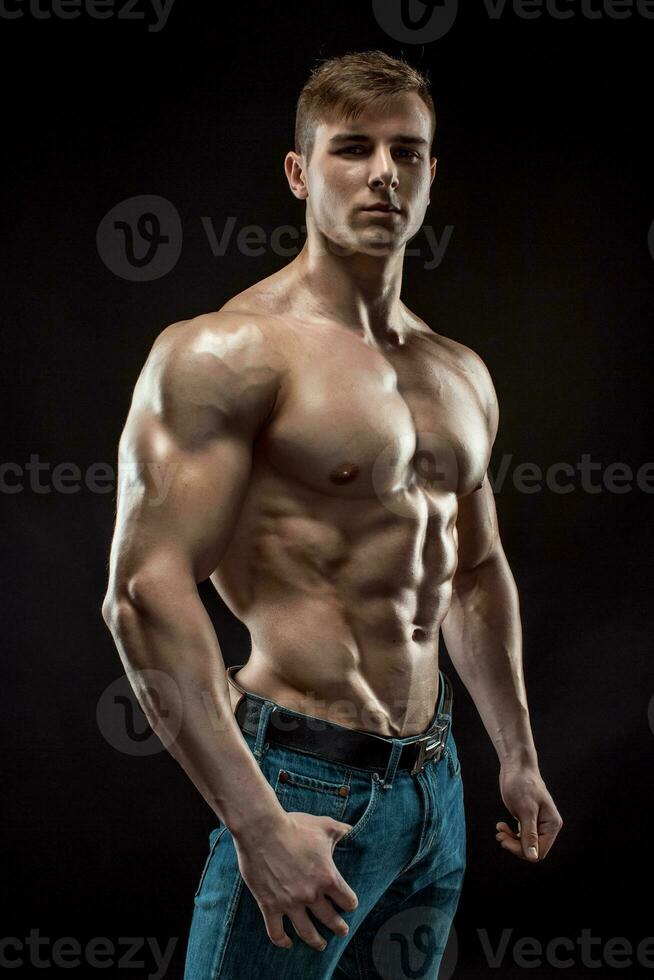 Muscular bodybuilder guy doing posing over black background photo