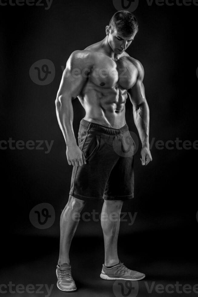 Muscular bodybuilder guy doing posing over black background photo