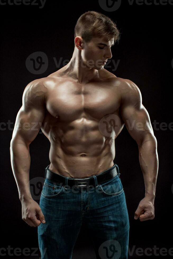 Muscular bodybuilder guy doing posing over black background photo