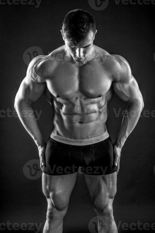 Muscular bodybuilder guy doing posing over black background photo