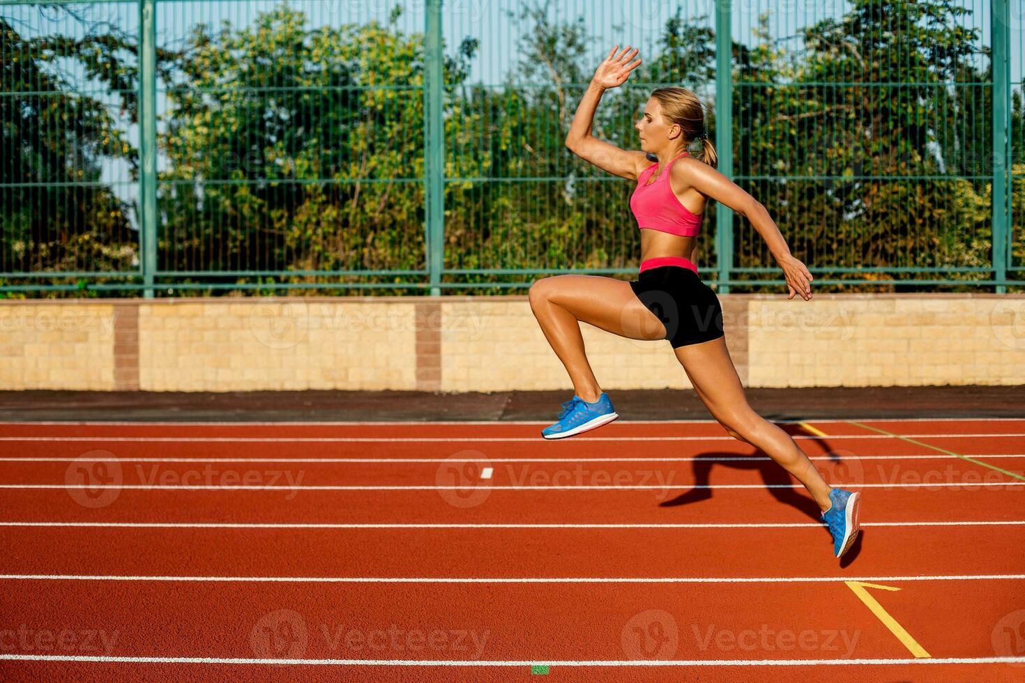 Side view beautiful young woman exercise jogging and running on athletic track on stadium photo