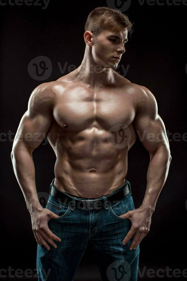 Muscular bodybuilder guy doing posing over black background photo