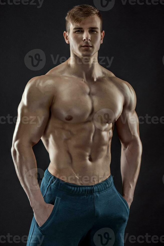 Muscular bodybuilder guy doing posing over black background photo