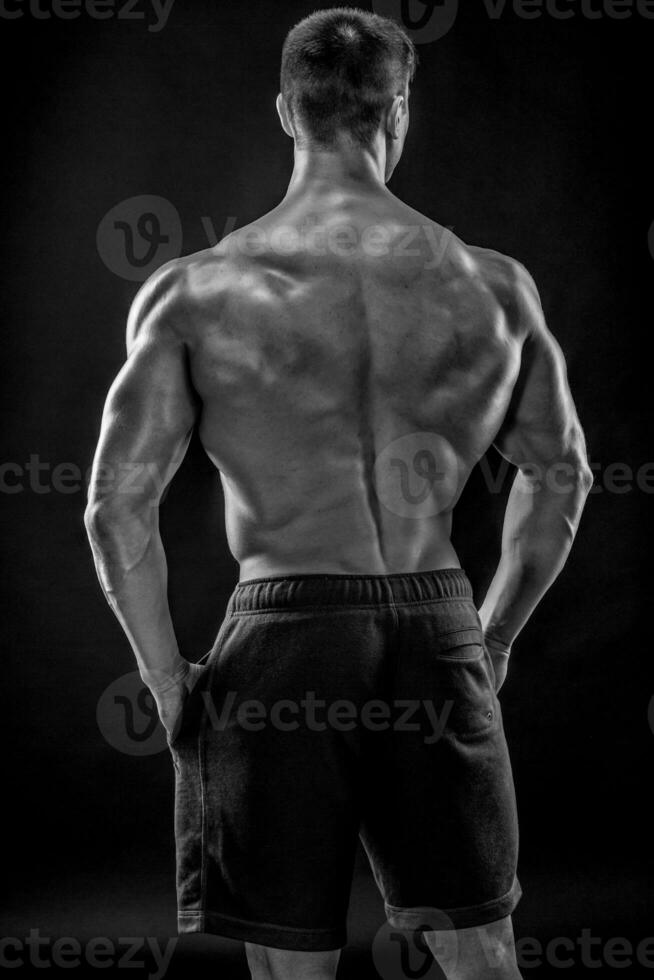 Muscular bodybuilder guy doing posing over black background photo