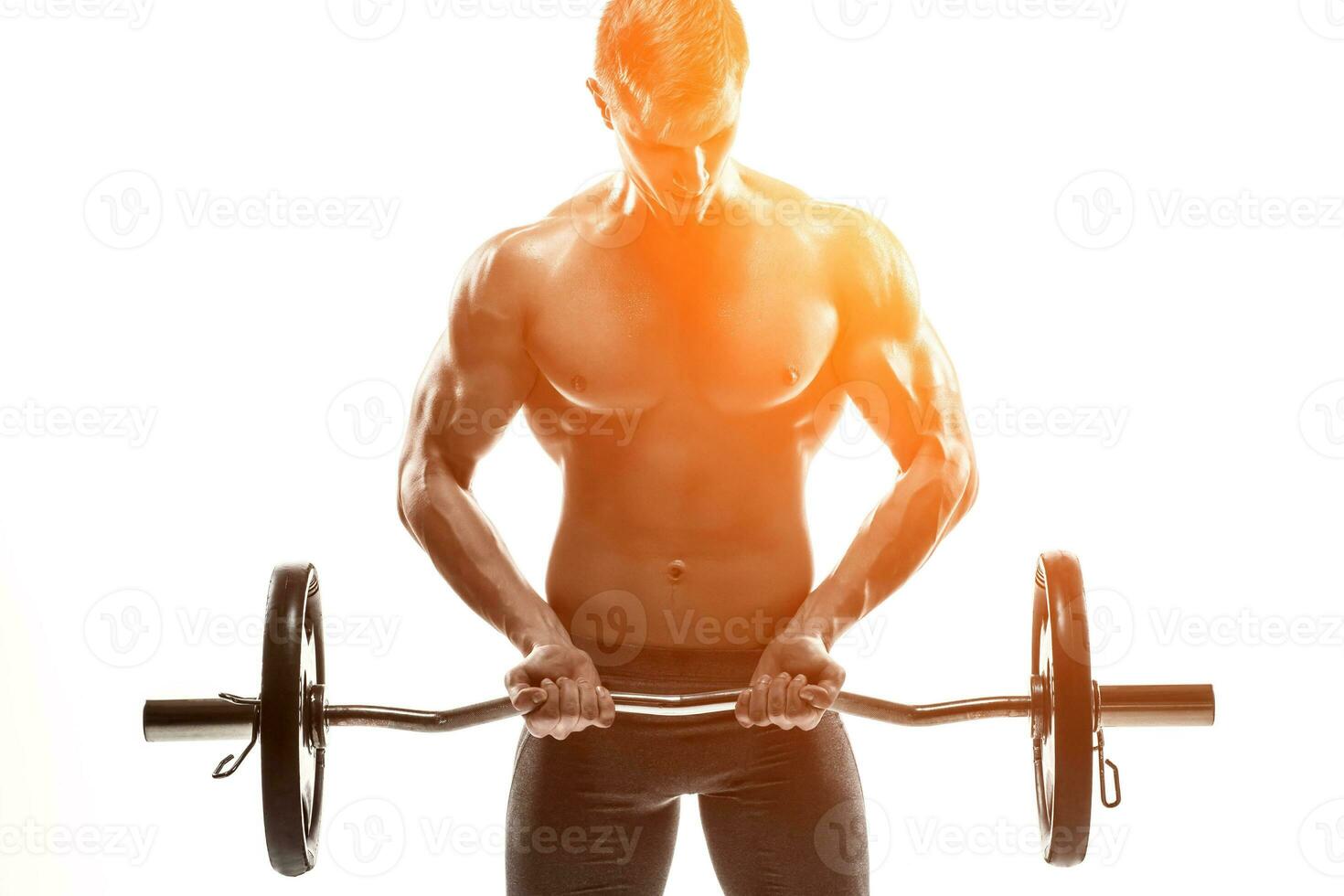 Young handsome man with naked torso and barbell photo