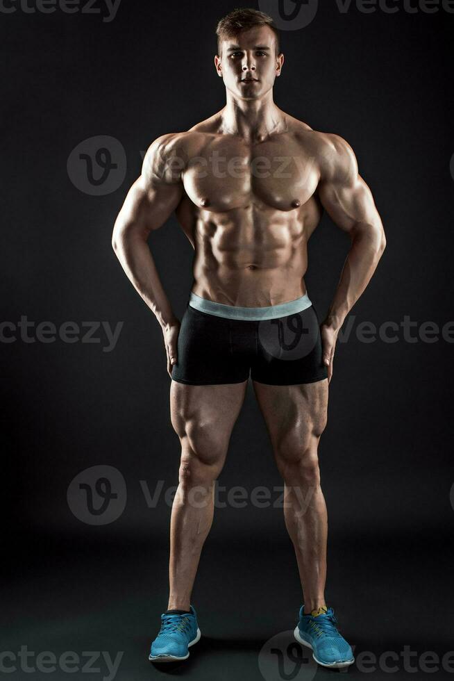 Muscular bodybuilder guy doing posing over black background photo