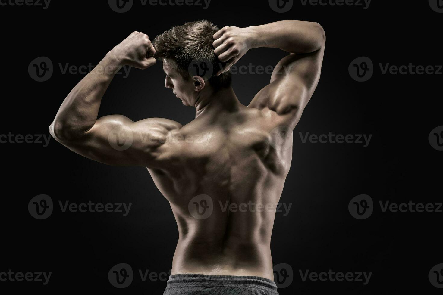 Healthy muscular young man showing back and biceps muscles photo