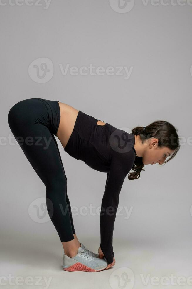 Woman doing stretching forward bends on grey background photo