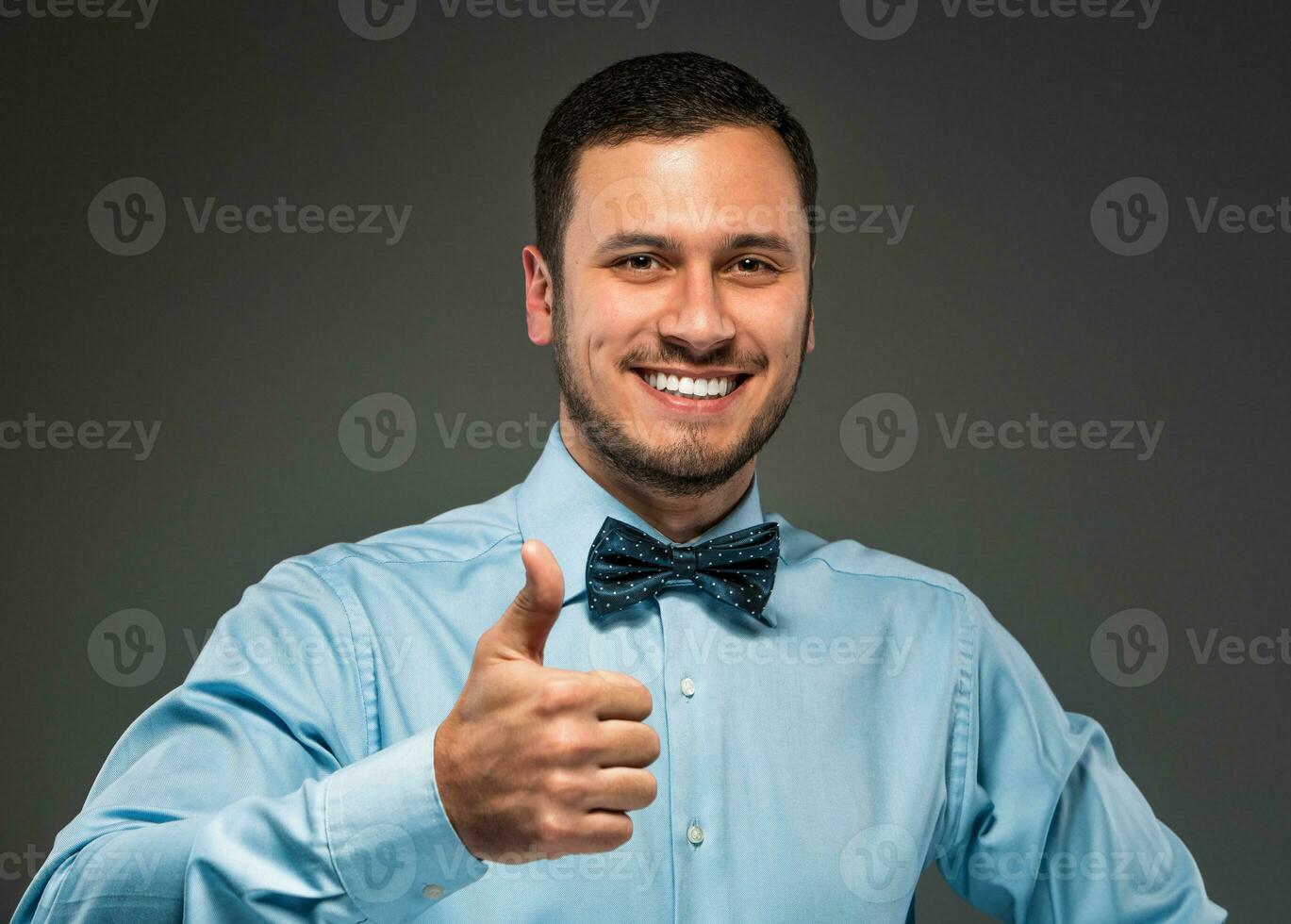 Smiling young man making the ok thumbs up hand sign photo