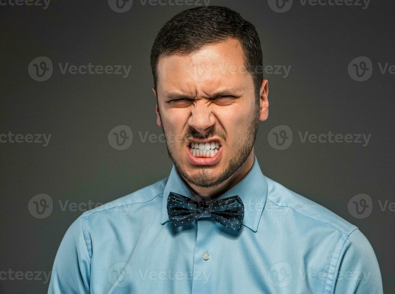 Portrait angry upset young man in blue shirt, butterfly tie photo