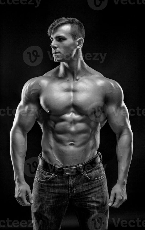 Muscular bodybuilder guy doing posing over black background photo