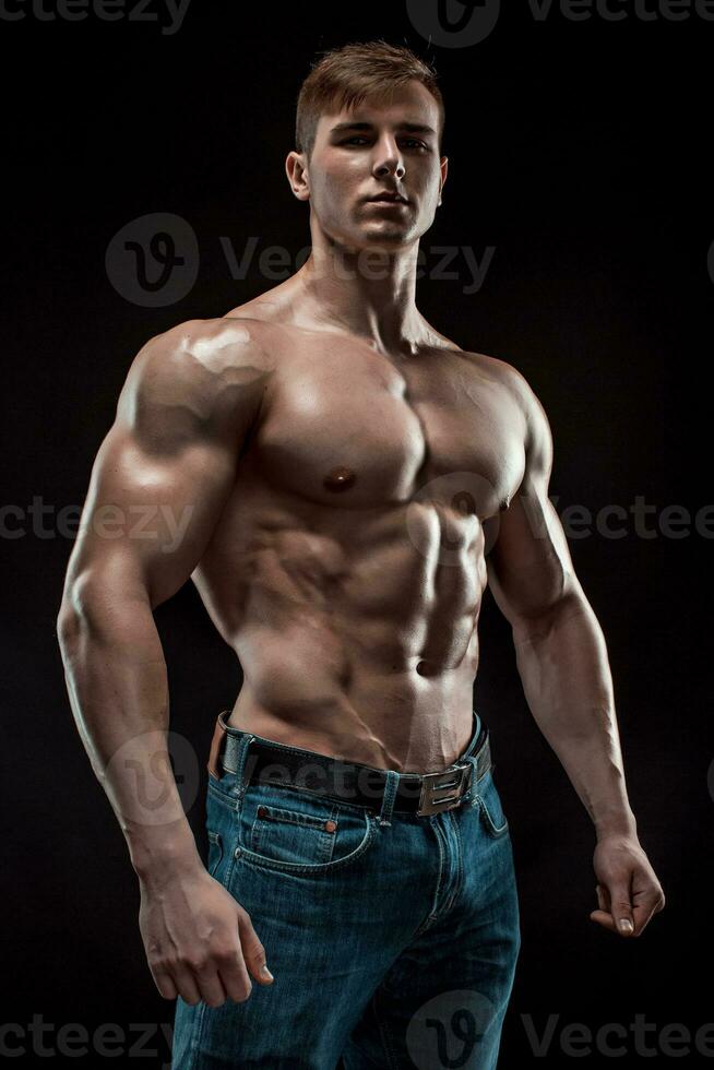 Muscular bodybuilder guy doing posing over black background photo