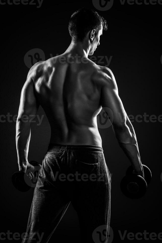 Fitness man showing his gread body with dumbbells, rear view photo