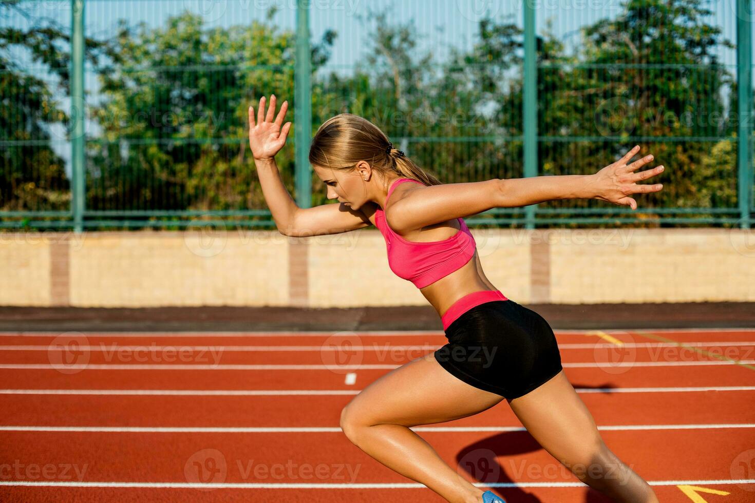Side view beautiful young woman exercise jogging and running on athletic track on stadium photo