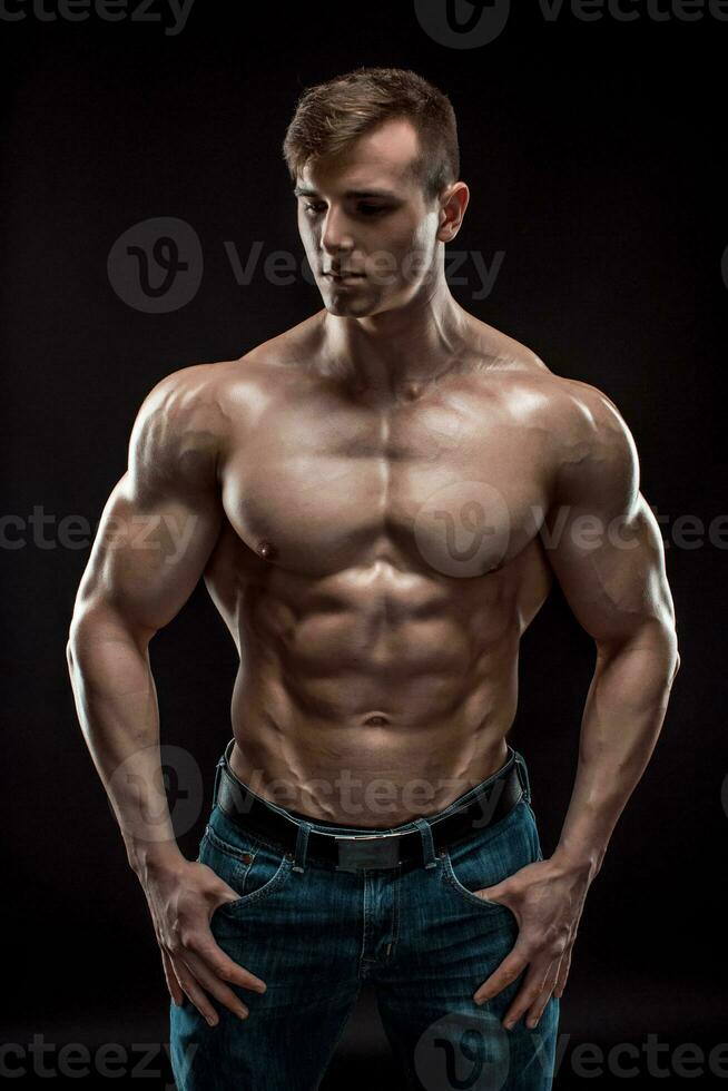 Muscular bodybuilder guy doing posing over black background photo
