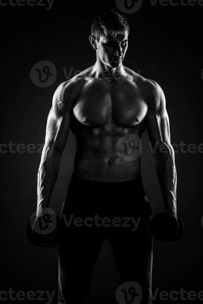 muscular hombre demostración Perfecto cuerpo con pesas en negro backgr foto