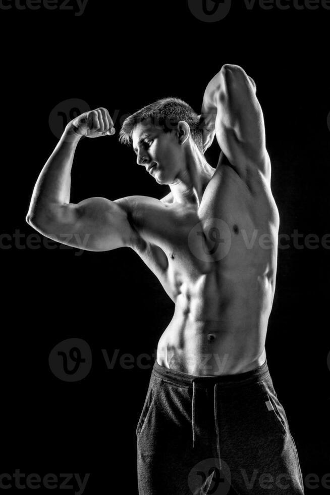 Strong man showing perfect abs, houlders, biceps, triceps and ch photo