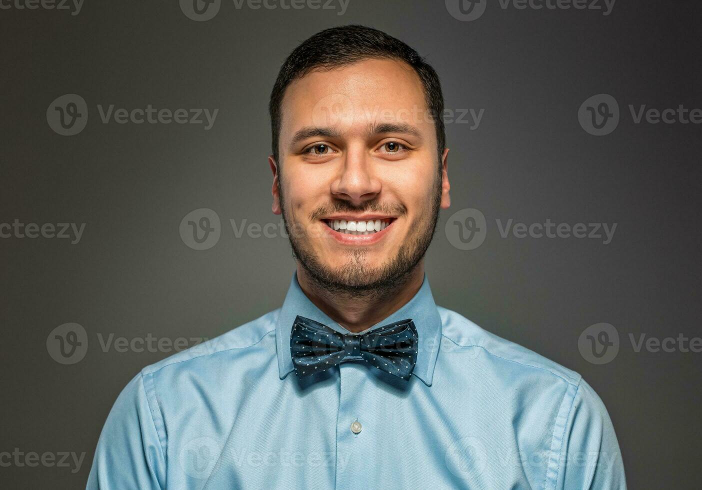 Smiling young man in blue shirt and butterfly tie photo