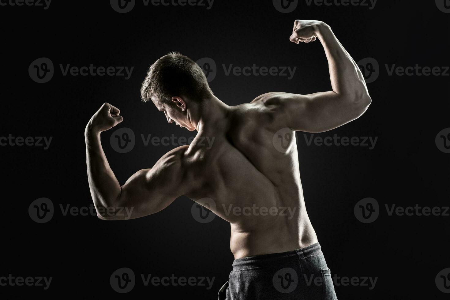 Rear view of muscular young man showing back, biceps muscles photo