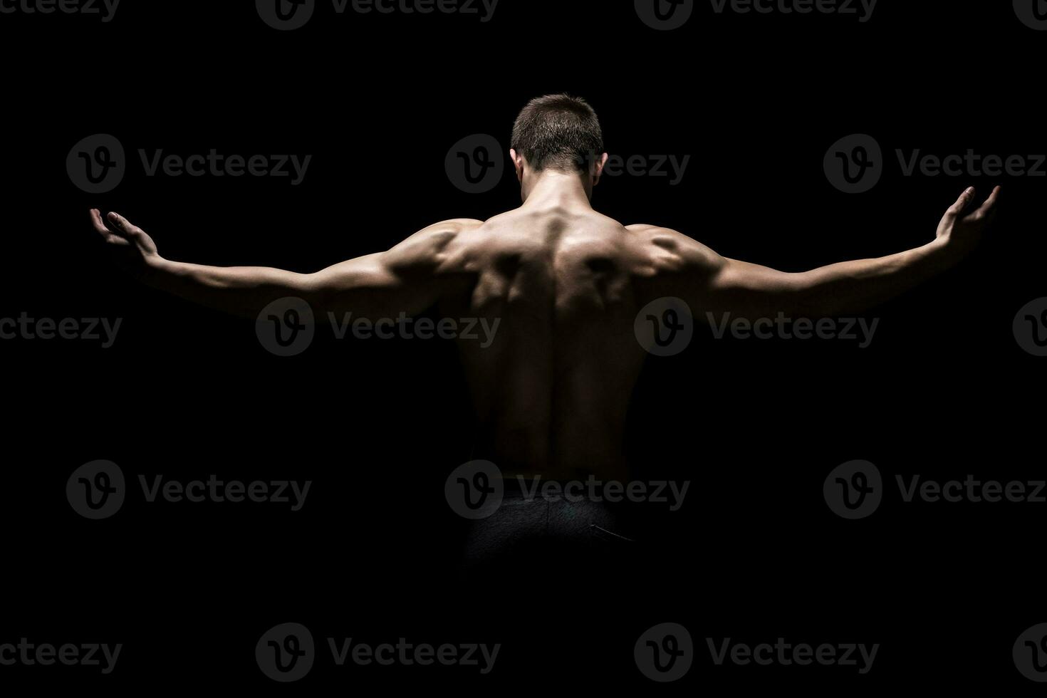 Rear view of muscular man with his arms stretched out photo