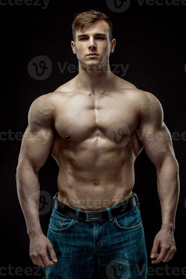 Muscular bodybuilder guy doing posing over black background photo