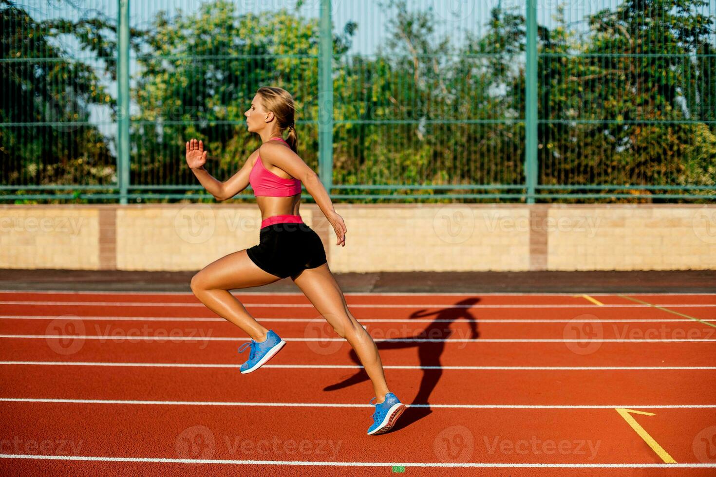 Side view beautiful young woman exercise jogging and running on athletic track on stadium photo