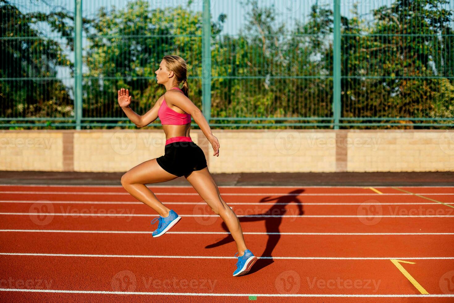 lado ver hermosa joven mujer ejercicio trotar y corriendo en atlético pista en estadio foto