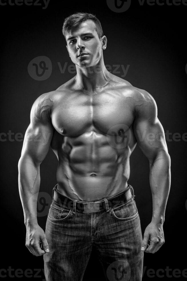 Muscular bodybuilder guy doing posing over black background photo