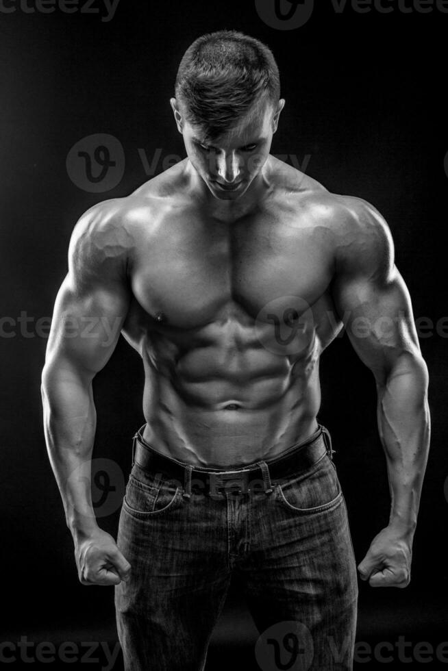 Muscular bodybuilder guy doing posing over black background photo