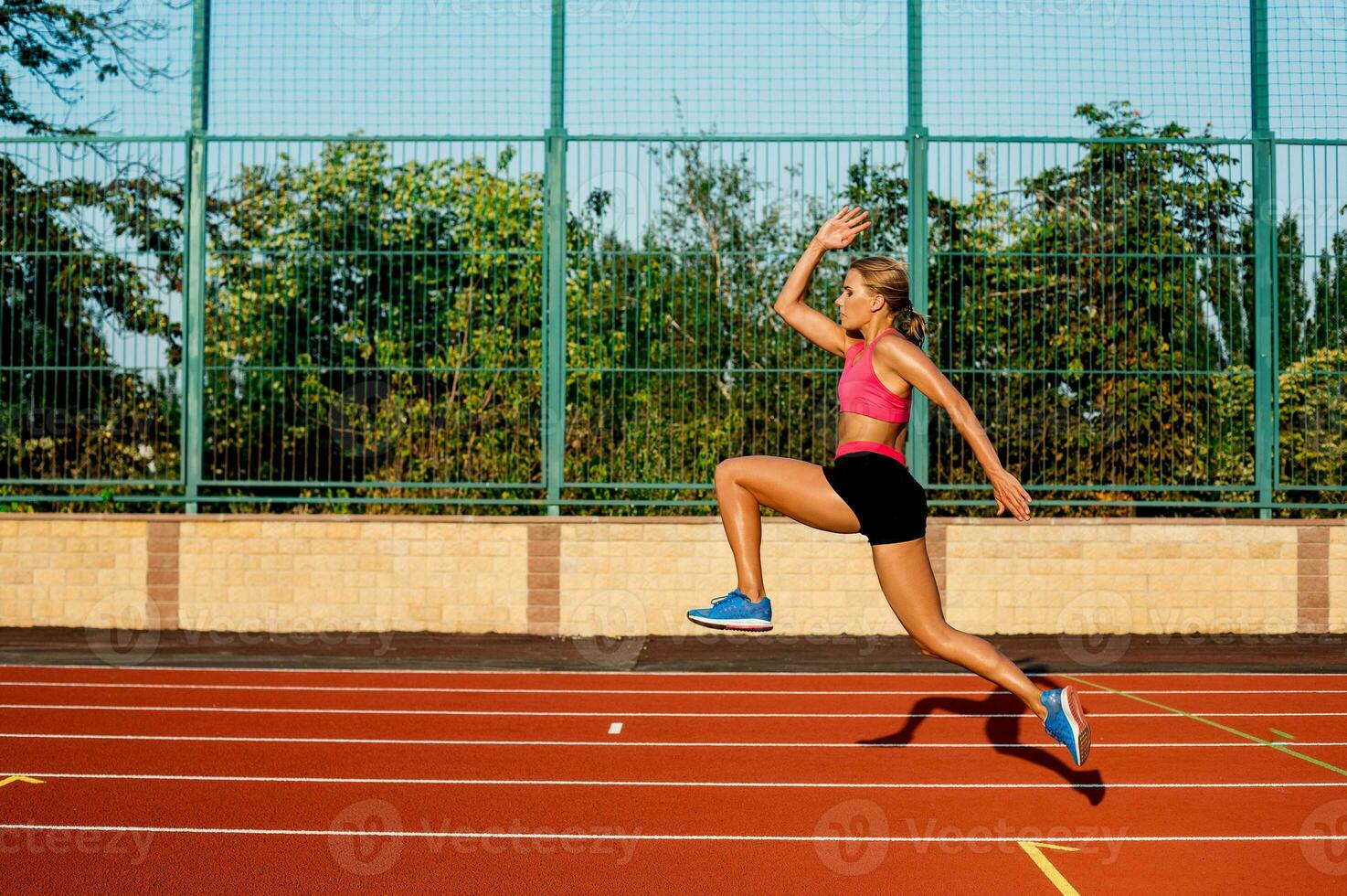 Side view beautiful young woman exercise jogging and running on athletic track on stadium photo