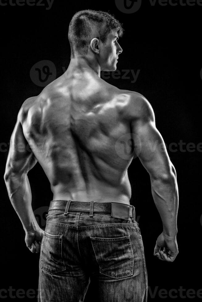 Muscular bodybuilder guy doing posing over black background photo