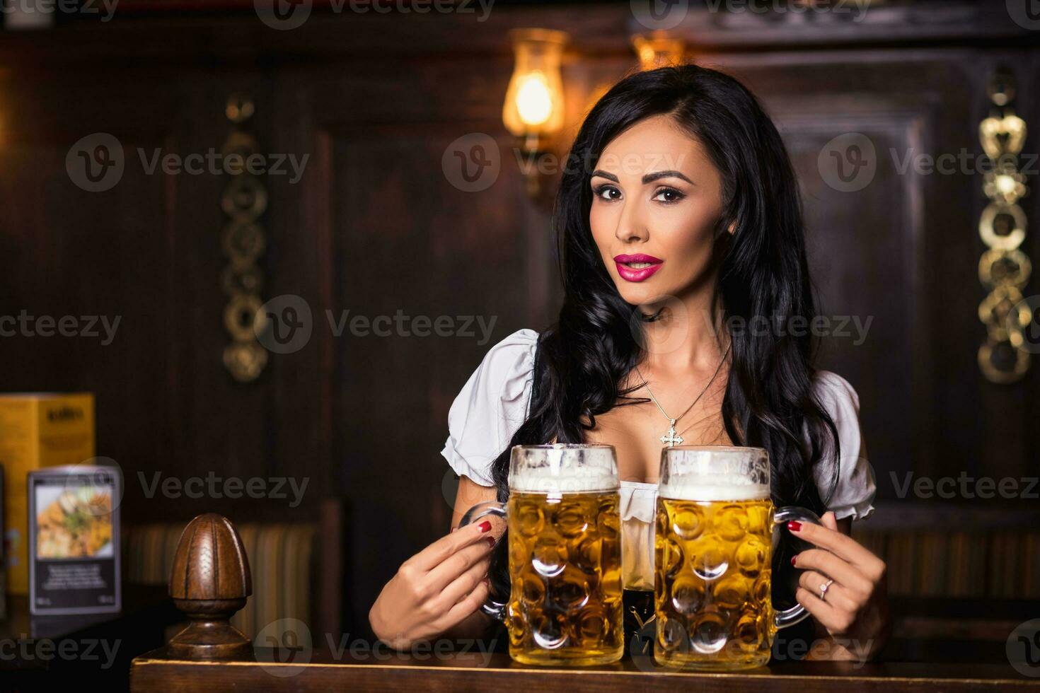 Oktoberfest. Brunette woman holding beer mugs in bar photo