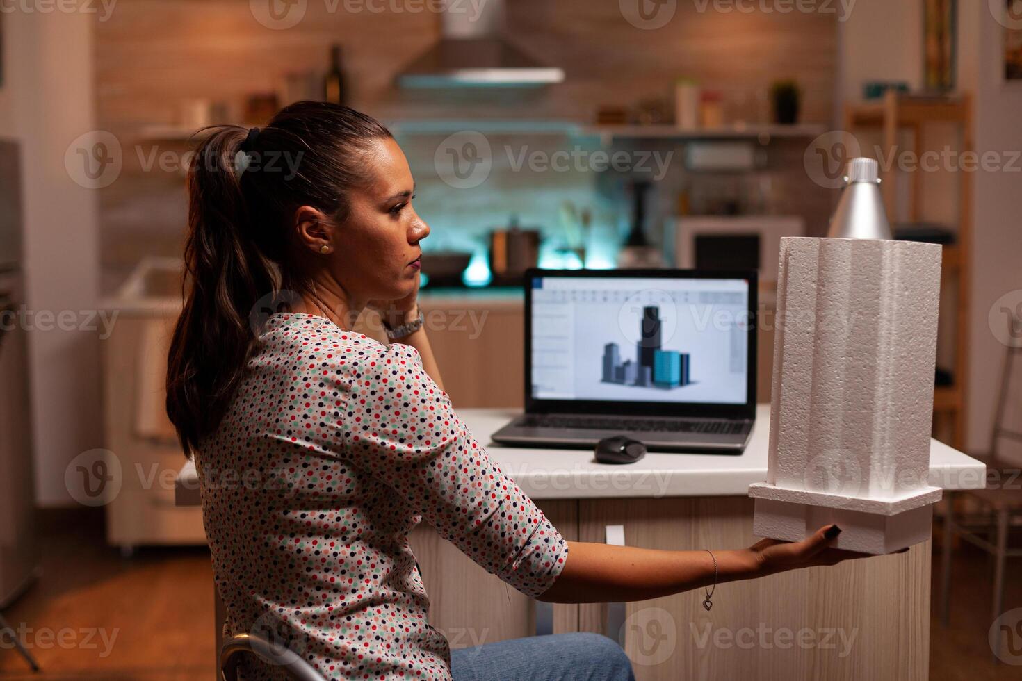 Serious architect working on a housing project holding a building model during late night time. Engineer artist creating and working in office holding scale building model, determination, career. photo