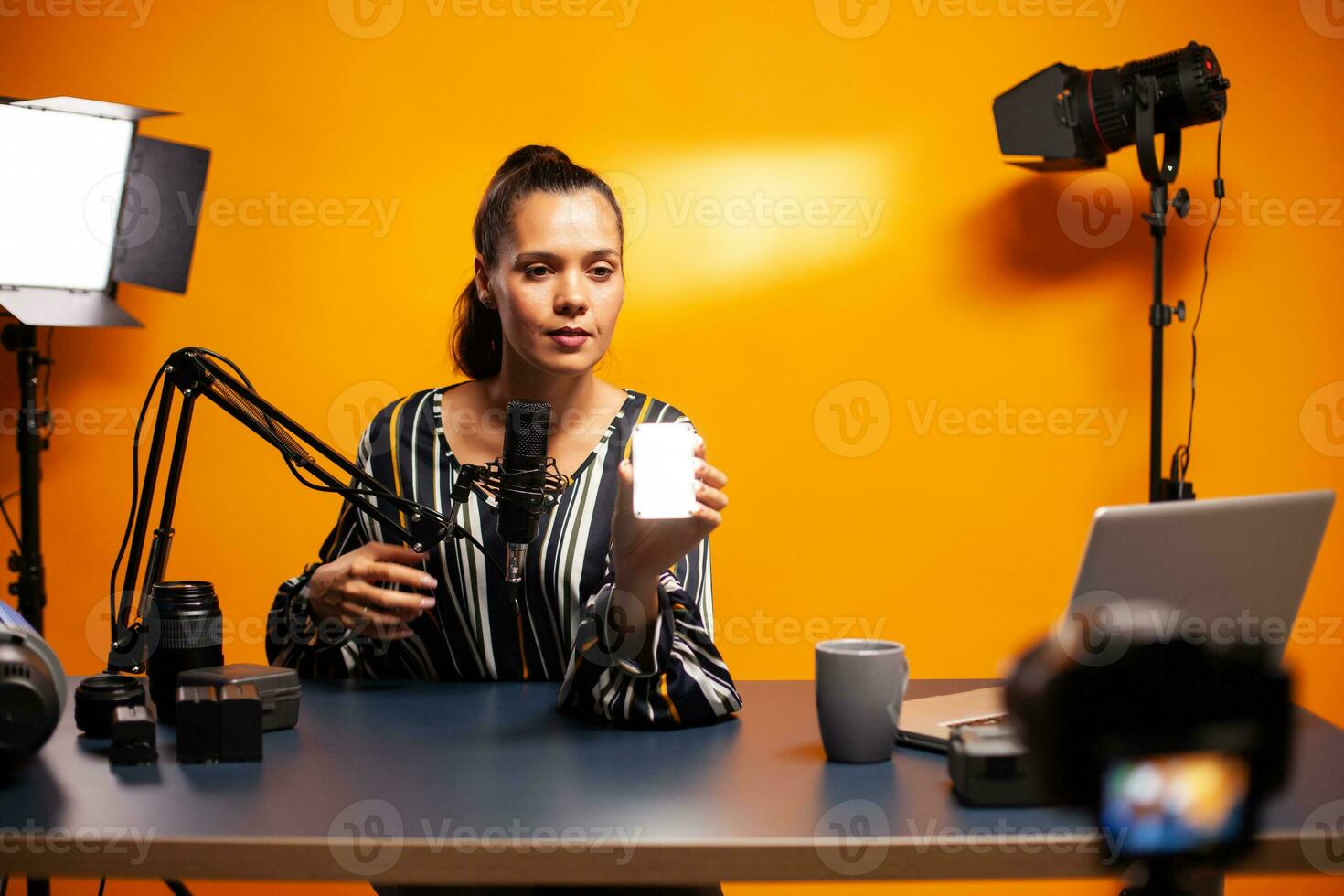 Filmmaker showing mini led light while recording podcast. Video blogger recording a vlog with technology product equipment use in videography and photography. photo