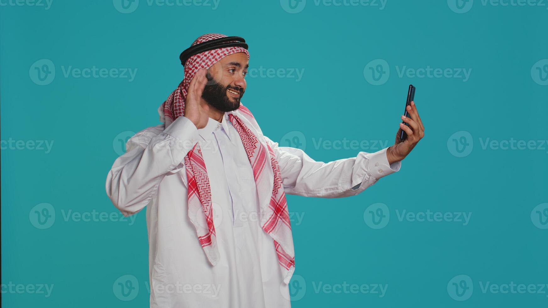 Arab person greeting people on call, waving and catching up with friends on remote network connection. Middle eastern adult in traditional islamic clothing discussing on teleconference. photo