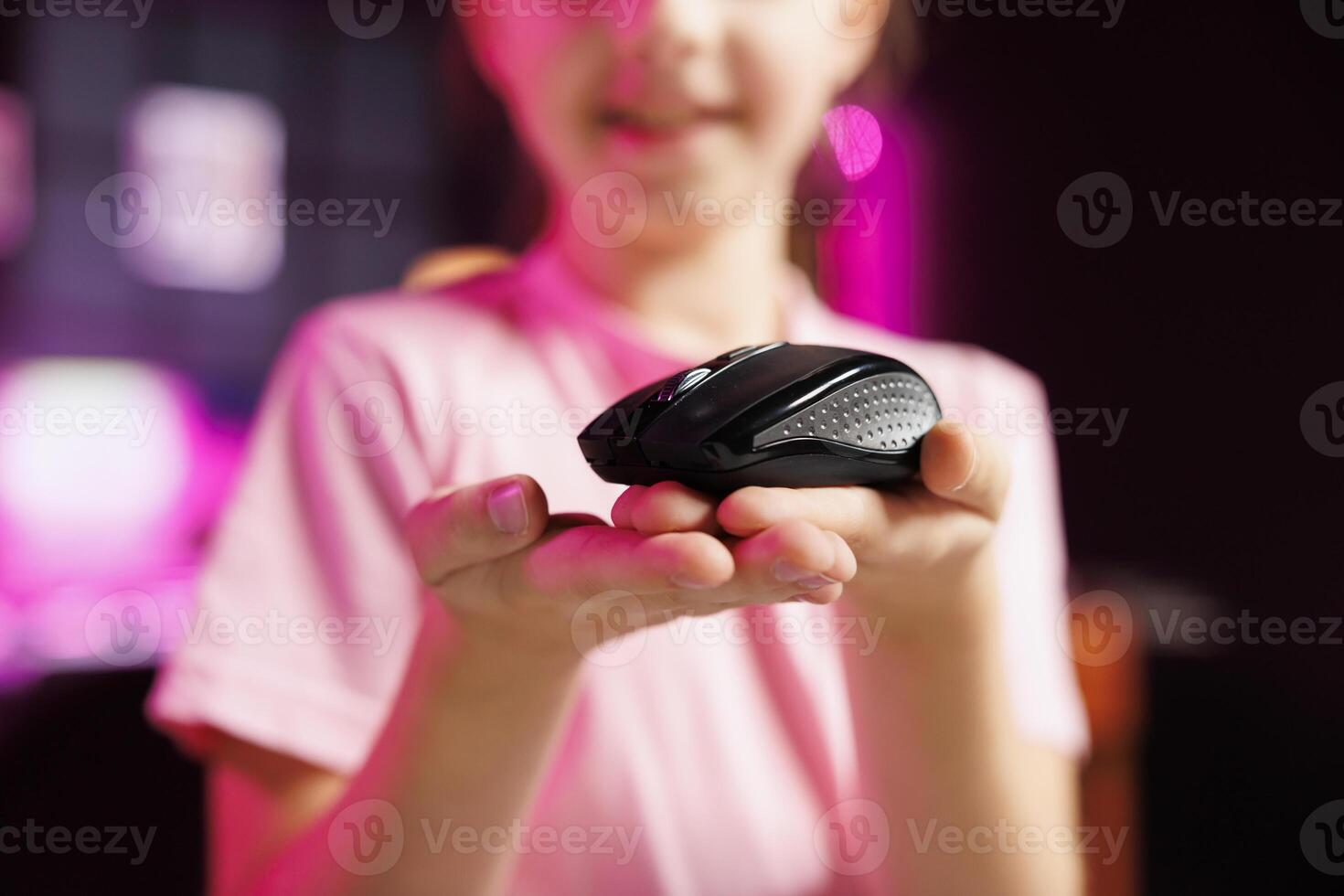 Close up on mouse received by cute girl from sponsoring brand to promote it. Focus on wireless Bluetooth computer peripheral advertised by young child in blurry background doing influencer marketing photo