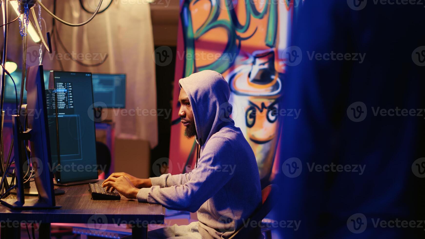 Rogue programmer welcoming new member in hacking group, showing him around underground hideout and explaining work they do. Hacker doing graffiti painted criminals den tour to colleague photo