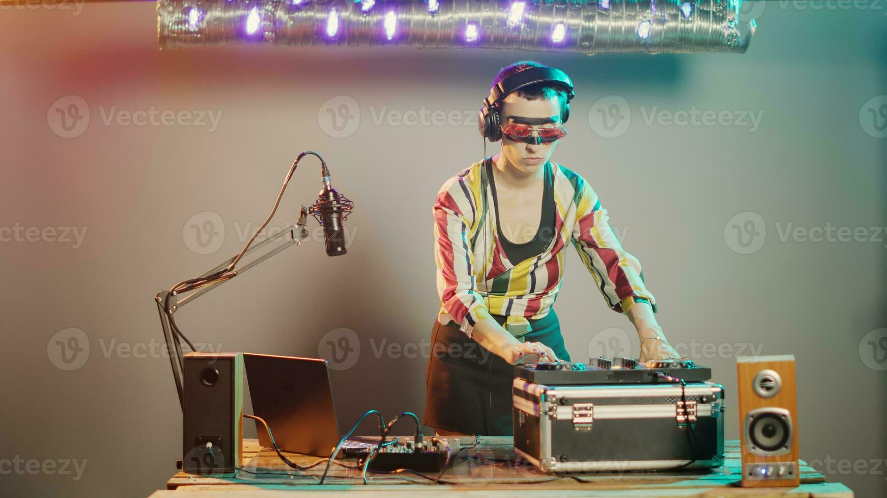 Disc jockey gives thumbs down on stage after mixing stereo sounds at turntables, showing dislike and disapproval sign while she uses mixer keys. Expressing rejection and disagreement. Tripod shot. photo