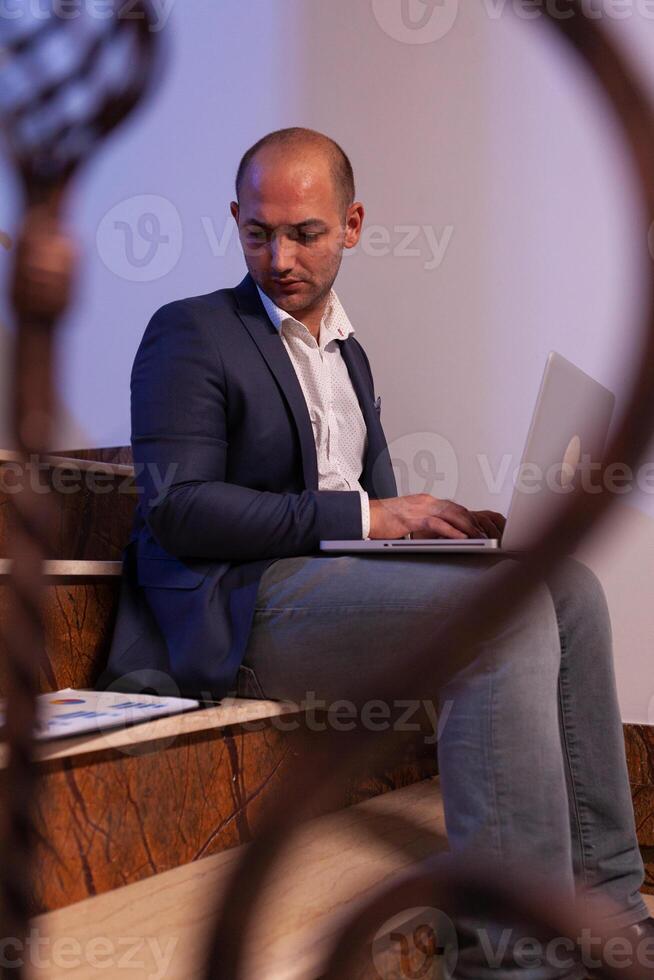 Tired stressed businessman lose concentration on business deadline at workplace. Corporate entrepreneur using laptop doing overtime sitting on stairwell. photo