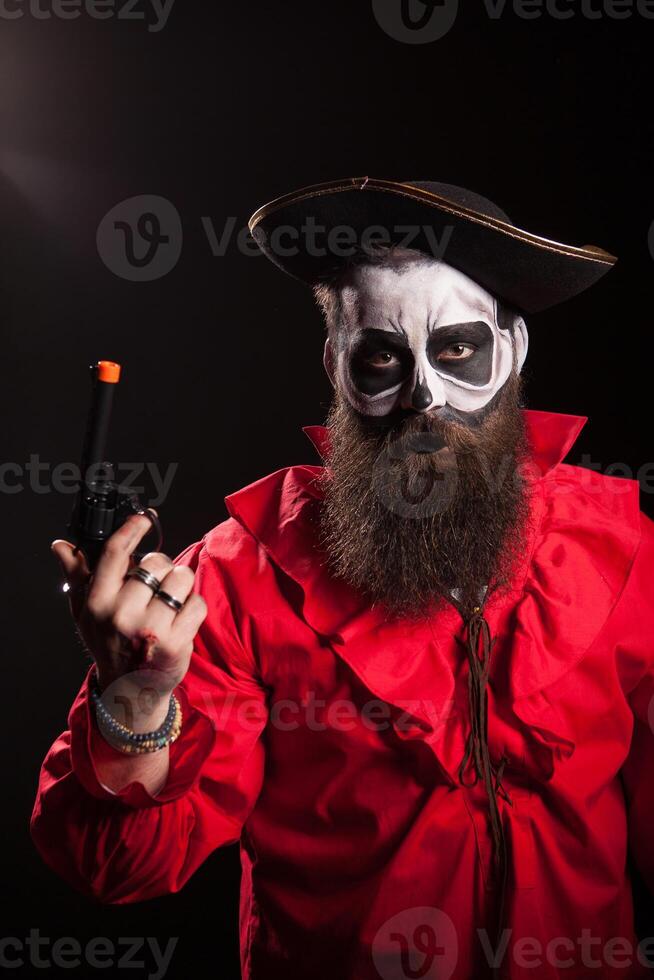 Crazy and spooky medieval pirate with his pistol over black background. Halloween outfit. photo