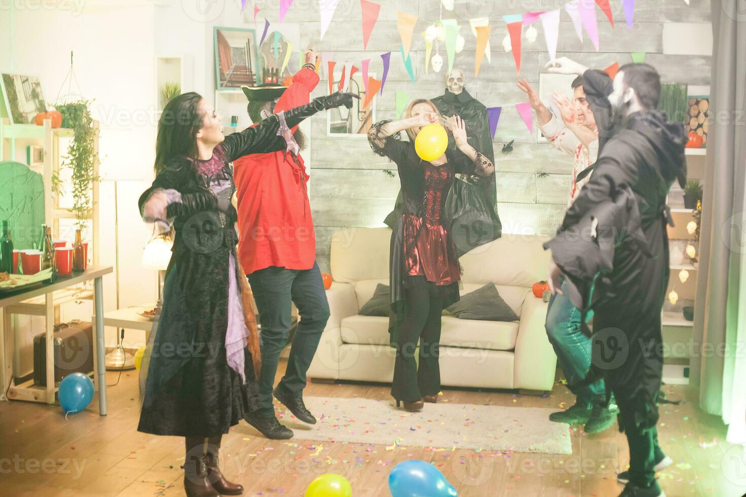 Witch dancing with hands up at halloween party. Spooky costumes. photo