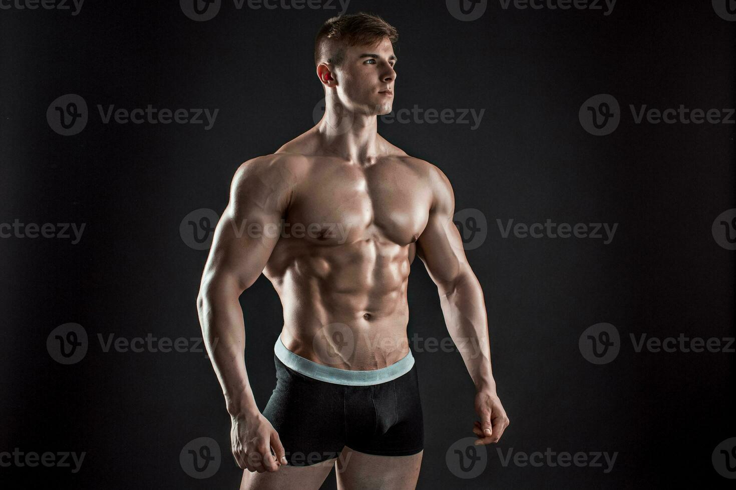 Muscular bodybuilder guy doing posing over black background photo