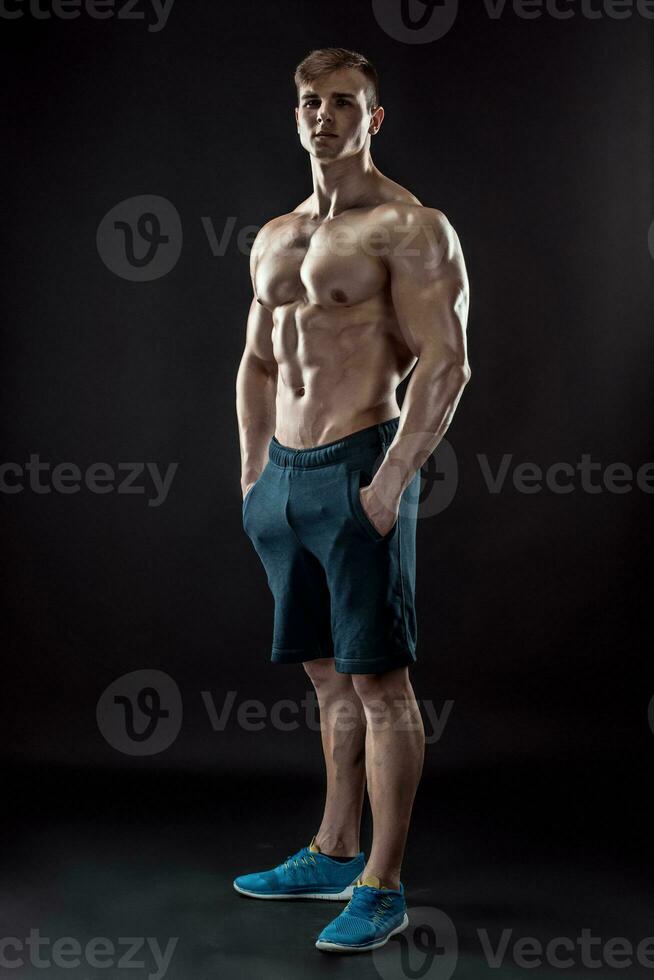 Muscular bodybuilder guy doing posing over black background photo