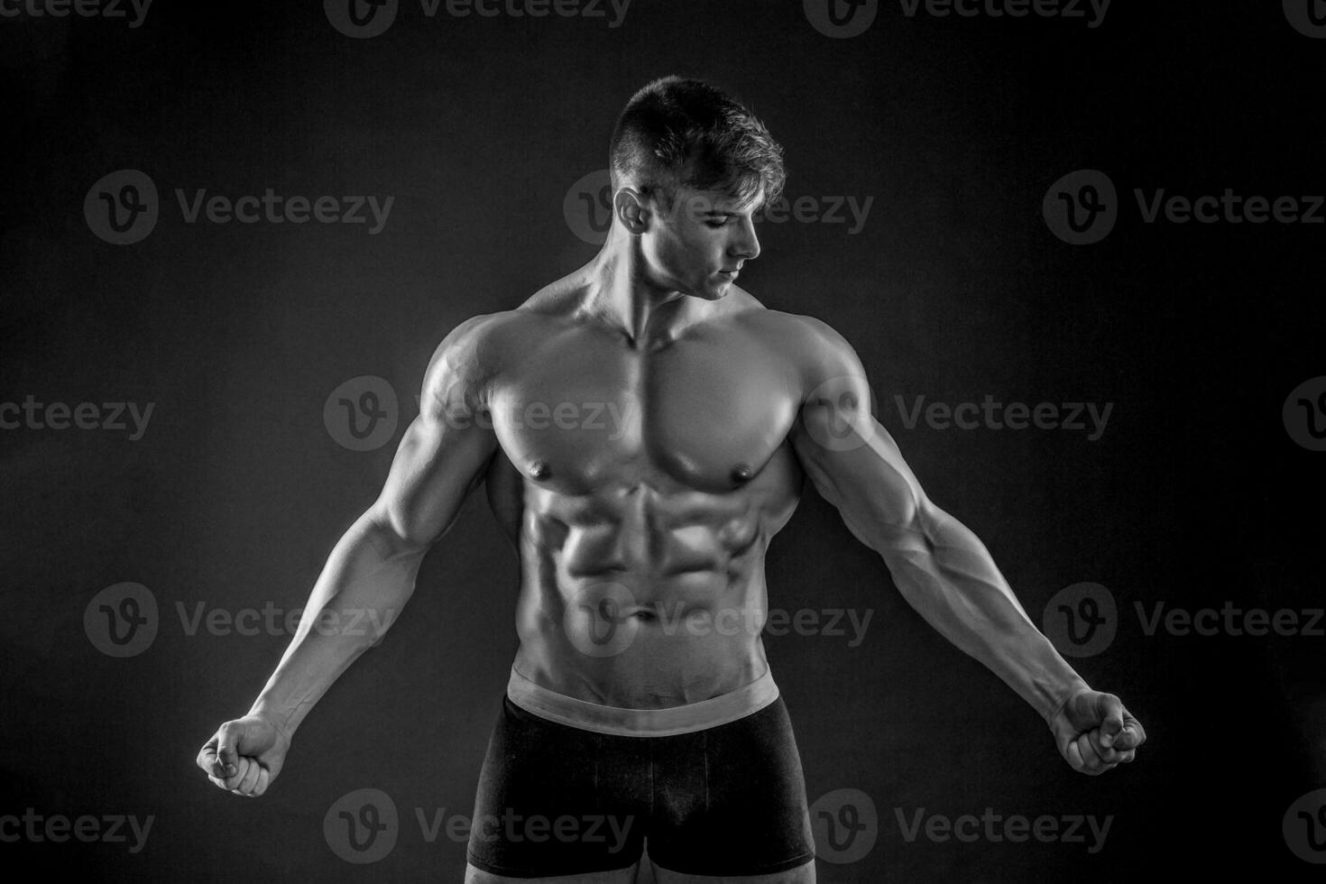 Muscular bodybuilder guy doing posing over black background photo