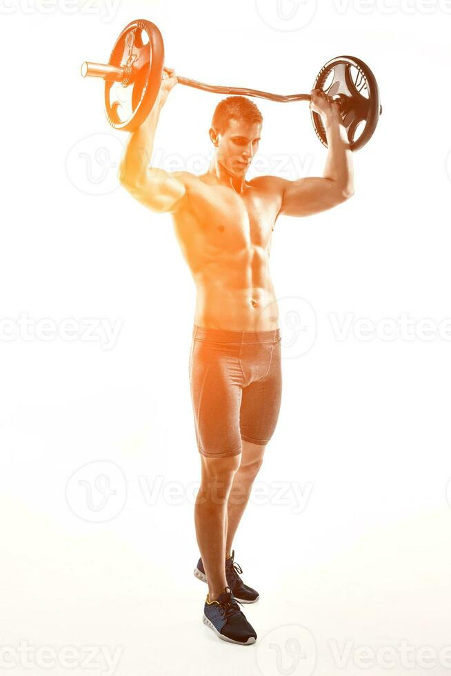 Muscular man standing on knee, holding barbell over his head photo