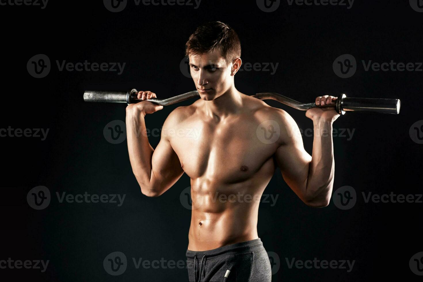 Strong man holding barbell on his shoulders, photo