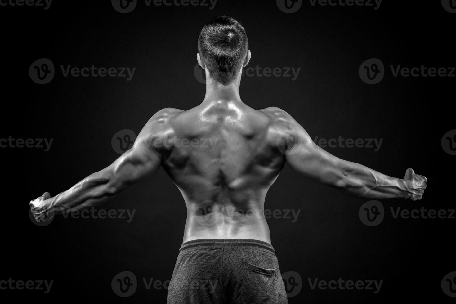 Rear view of muscular man with his arms stretched out photo
