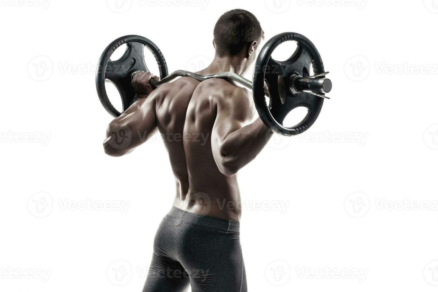 Muscular man holding a barbell on his shoulders, rear view. photo